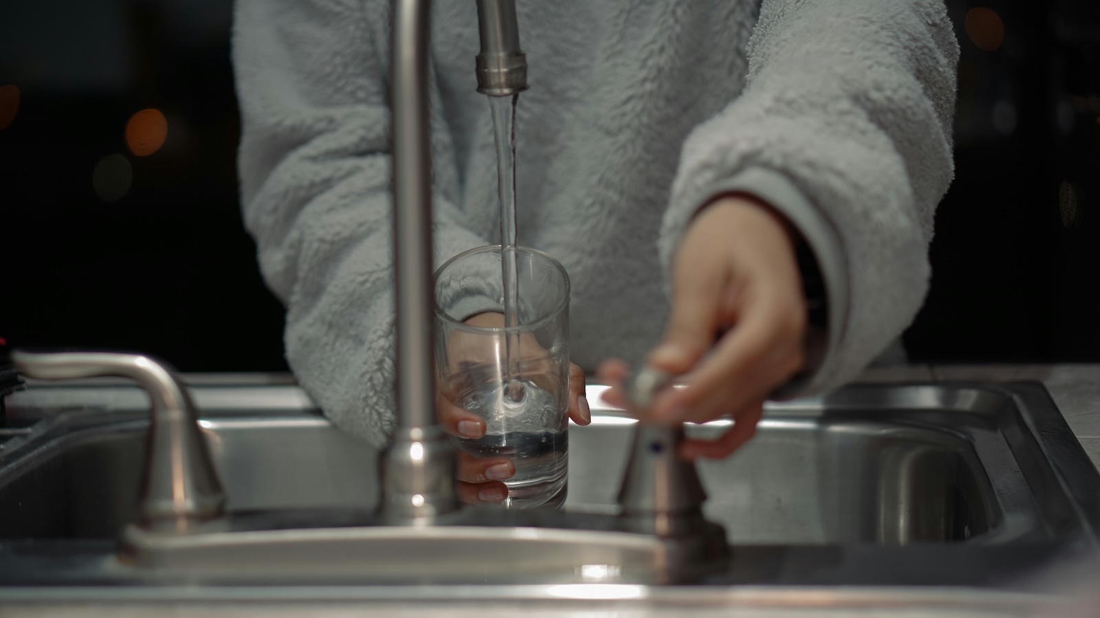 A clear glass of tap water held to the light — arsenic is colorless, odorless, and tasteless, so it can only be confirmed by a laboratory test.