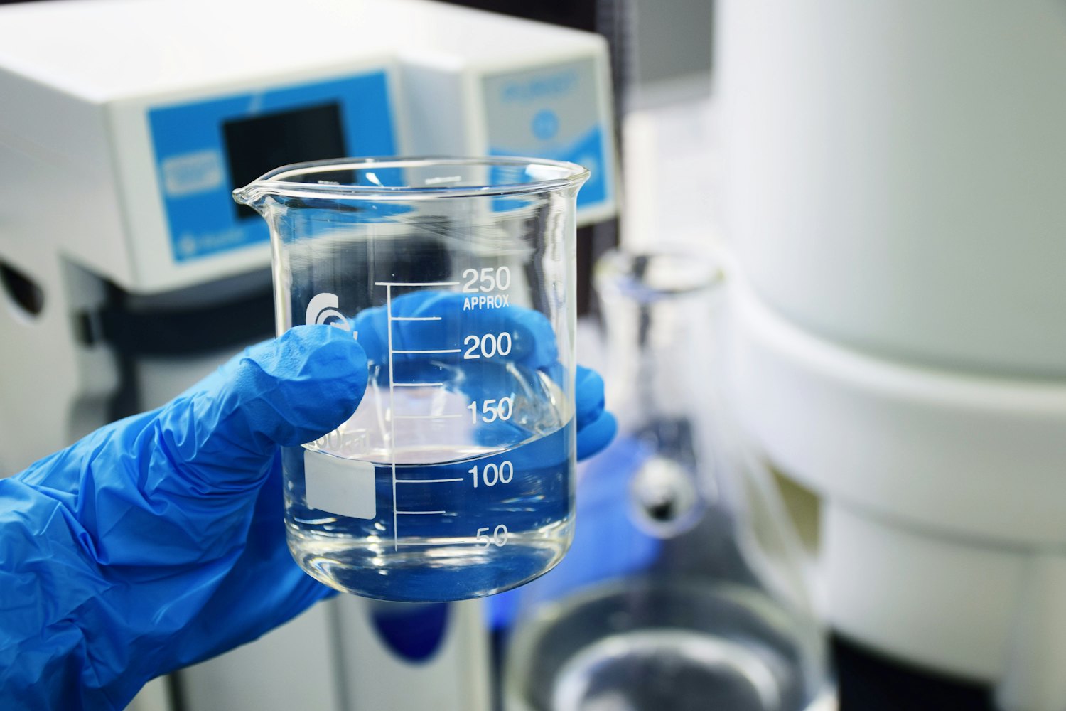 A clear glass measuring vessel of water on a white surface — the WQA Gold Seal certifies finished water-treatment products to NSF/ANSI standards.